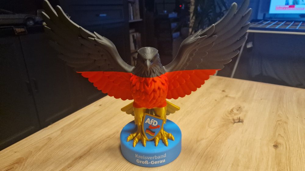 Adler-Figur in Schwarz-Rot-Gold mit AfD-Wappen und Deutschlandfahne auf blauem Sockel mit der Aufschrift Kreisverband Groß-Gerau